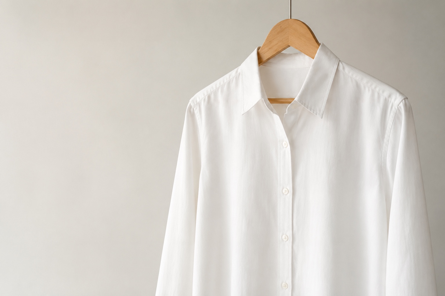 Camisa branca em cabide de madeira clara, peça atemporal